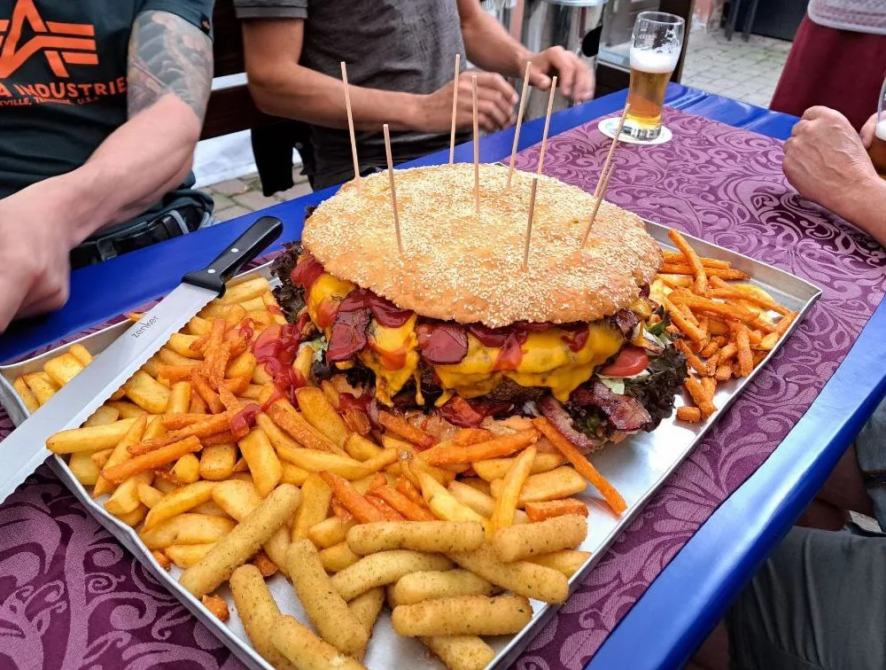 Dora Burger auf dem Tisch, riesiger Burger mit Pommes und Süßkartoffelpommes im Freien