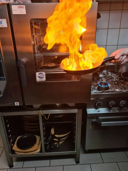 Flambierende Pfanne in der Schlossgewölbe-Küche, frisch zubereitet mit offener Flamme